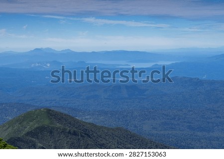 Panoramic mountain view while hiking Mount Shari in eastern Hokkaido, Japan. A panoramic view of green mountains and vast forests seen while hiking Mount Shari in eastern Hokkaido, Japan. This expansive landscape represents mountain trekking, outdoor adventure, nature, and scenic tourism in northern Japan.