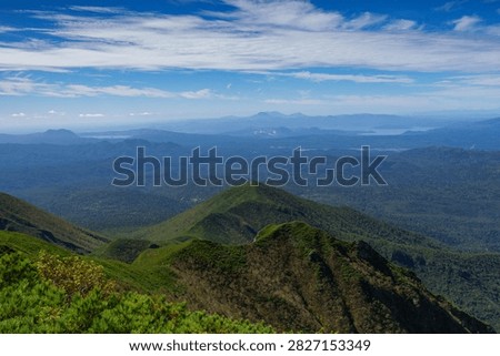 Panoramic mountain view while hiking Mount Shari in eastern Hokkaido, Japan. A panoramic view of green mountains and vast forests seen while hiking Mount Shari in eastern Hokkaido, Japan. This expansive landscape represents mountain trekking, outdoor adventure, nature, and scenic tourism in northern Japan.