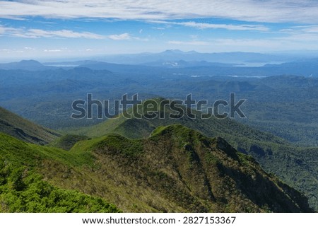 Panoramic mountain view while hiking Mount Shari in eastern Hokkaido, Japan. A panoramic view of green mountains and vast forests seen while hiking Mount Shari in eastern Hokkaido, Japan. This expansive landscape represents mountain trekking, outdoor adventure, nature, and scenic tourism in northern Japan.