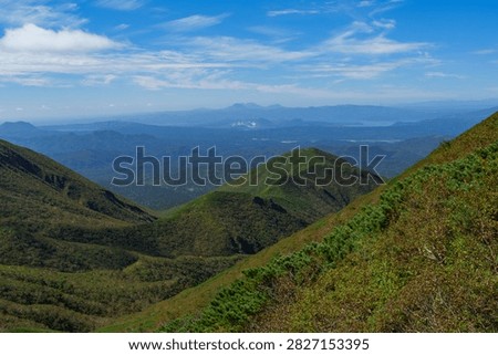 Panoramic mountain view while hiking Mount Shari in eastern Hokkaido, Japan. A panoramic view of green mountains and vast forests seen while hiking Mount Shari in eastern Hokkaido, Japan. This expansive landscape represents mountain trekking, outdoor adventure, nature, and scenic tourism in northern Japan.