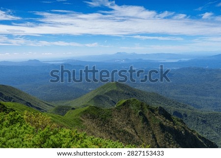Panoramic mountain view while hiking Mount Shari in eastern Hokkaido, Japan. A panoramic view of green mountains and vast forests seen while hiking Mount Shari in eastern Hokkaido, Japan. This expansive landscape represents mountain trekking, outdoor adventure, nature, and scenic tourism in northern Japan.