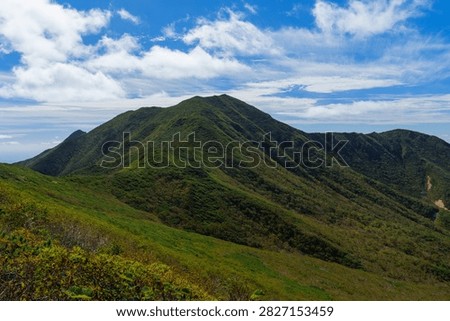 Panoramic mountain view while hiking Mount Shari in eastern Hokkaido, Japan. A panoramic view of green mountains and vast forests seen while hiking Mount Shari in eastern Hokkaido, Japan. This expansive landscape represents mountain trekking, outdoor adventure, nature, and scenic tourism in northern Japan.