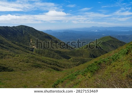 Panoramic mountain view while hiking Mount Shari in eastern Hokkaido, Japan. A panoramic view of green mountains and vast forests seen while hiking Mount Shari in eastern Hokkaido, Japan. This expansive landscape represents mountain trekking, outdoor adventure, nature, and scenic tourism in northern Japan.