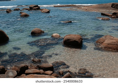 panoramic, natural pool in the sea, foreground, clear water, sand, rocks, in the background, small stone barrier, sea - Powered by Shutterstock