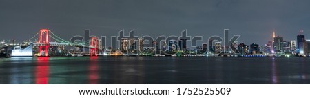 Panoramic nightview of Rainbow Bridge, illuminated in red as a sign of 