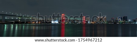 Panoramic nightview of Rainbow Bridge illuminated in red as a sign of Tokyo Alert, coronavirus alert for Tokyo area, in Odaiba Japan.