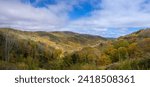 A panoramic photo of the Appalachian Mountains in autumn, showcasing the vibrant hues of fall foliage covering the slopes and valleys. From an overlook on the Cherohala Skyway, 