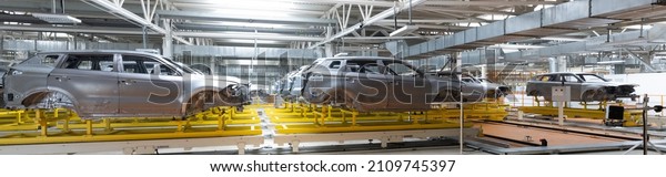Panoramic photo of car\
bodies are on assembly line. Factory for production of cars. Modern\
automotive industry
