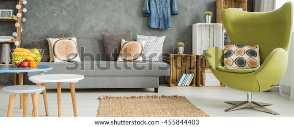 Panoramic photo of a colorful apartment\
with a green egg chair and a set of coffee\
tables