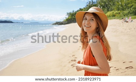 Panoramic photo of smiling girl in straw hat and sundress turning without looking into the camera on beautiful empty sunny tropical beach. Banner ad and copy space.