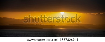 panoramic photo of the sun setting over a lake