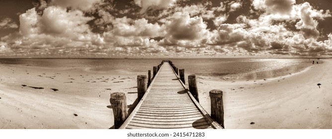 Panoramic photo taken from a wooden jetty on the Wadden Sea of the North Sea with a cloudy sky above the horizon - Powered by Shutterstock