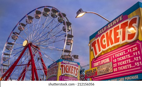 Panoramic Photo Of Ticket Sale Booth In A Theme Park With A Ferris Weheel On The Background At Sunset.