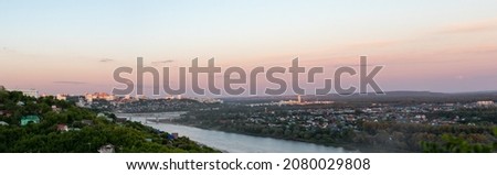Panoramic photo of Ufa skyline in city center with buildings, river, forest area on beautiful pink-blue sunset. Observation deck on city. Impression of traveler. Poster or postcard with view of city.