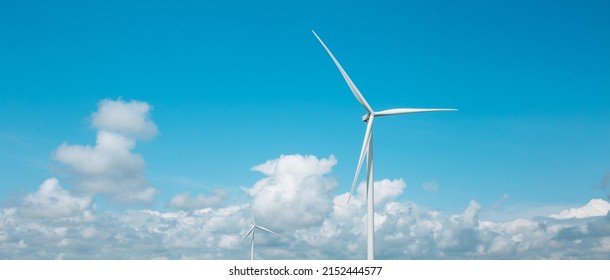 Panoramic photo of a windmill with high wind turbines for generation electricity against the blue sky. Renewable energy. Wide shot