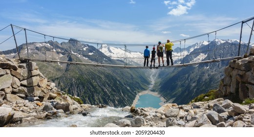 Panoramic picture of a family on a hike on the suspension bridge in the Zillertal with a view of the Schlegeis reservoir - Shutterstock ID 2059204430