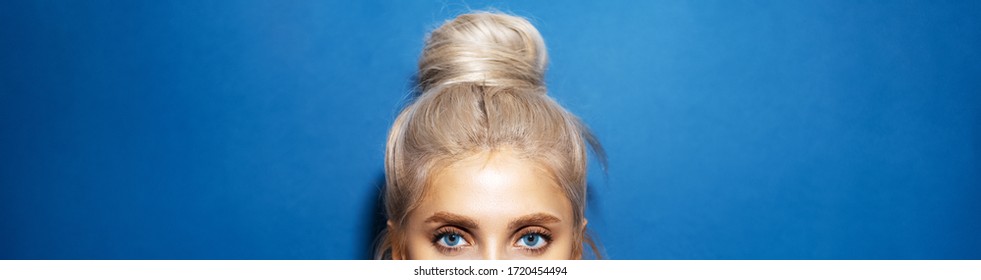 Panoramic Portrait Of Woman Head With Blue Eyes, Blonde Hair Wrapped In A Bun, On Background Of Phantom Blue Color.