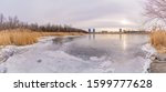 A panoramic scene of a frozen lake on Nuns Island. The lake is called: "Lac des battures" in french which means Lake of the Battures. The sun is above the skyline on a winter afternoon.