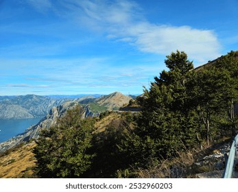 Panoramic Scenic View of the Bay of Kotor, Montenegro from a Mountain Summit on a Clear Day with Blue Sky, Lush Greenery, Distant Coastal Towns, and Majestic Mountains in the Background - Powered by Shutterstock