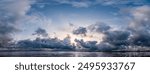 Panoramic shot of the dramatic sky during a storm with wispy clouds over the mudflats at the beginning of high tide on the North Sea island of Föhr