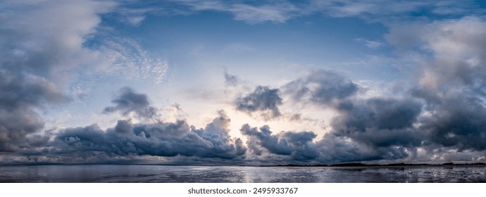 Panoramic shot of the dramatic sky during a storm with wispy clouds over the mudflats at the beginning of high tide on the North Sea island of Föhr - Powered by Shutterstock