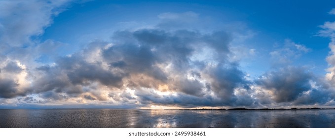 Panoramic shot of the dramatic sky during a storm with wispy clouds over the mudflats at the beginning of high tide on the North Sea island of Föhr