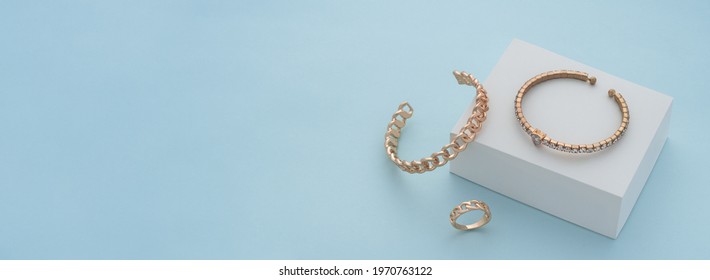 Panoramic shot of golden bracelets and ring on white box on blue background with copy space - Shutterstock ID 1970763122