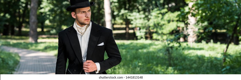 panoramic shot of handsome victorian man in hat standing outside 