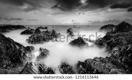 panoramic shot . long exposure rocky beach in black and white.