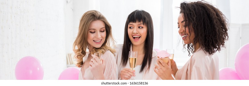 Panoramic Shot Of Multiethnic Girls Having Fun With Champagne And Cupcake During Bachelorette Party With Pink Balloons