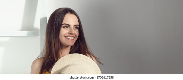 Panoramic shot of pretty girl smiling and holding a hat with copy space - Shutterstock ID 1703617858