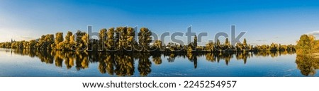 A panoramic shot of the reflection of the trees in the lake at sunset in Raunheim, Germany 