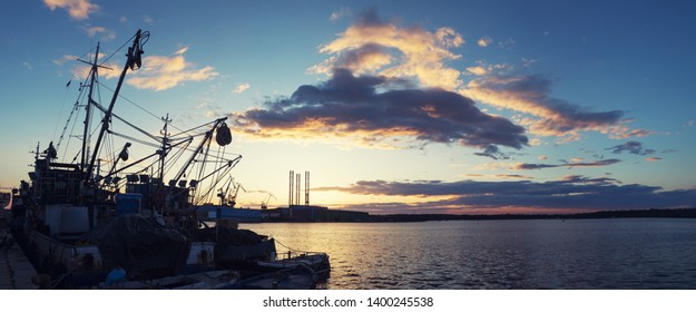 Panoramic Shot Of The Setting Sun Over Docks Of Pula, Istria, Croatia, Fishing Trawler Silhouette On The Left With Dramatic Clouds And Room For Adding Text, Copy Space, Super Wide Extra Large Panorama