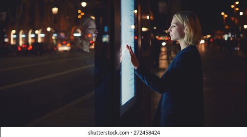 Panoramaaufnahme, Konzept der intelligenten Stadttechnik, Frau, die eine moderne Bushaltestelle in Barcelona benutzt, um Fahrpläne zu erfahren, Frauen, die große digitale Großbildschirme anfassen, die Licht reflektieren