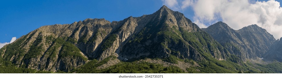 Panoramic shot of stunning mountain range with rugged peaks and lush greenery, blue sky with clouds, forest, alpine landscape. Tonale Pass, Italy. Summer vacation. Dolomite Alps. Ecology concept - Powered by Shutterstock