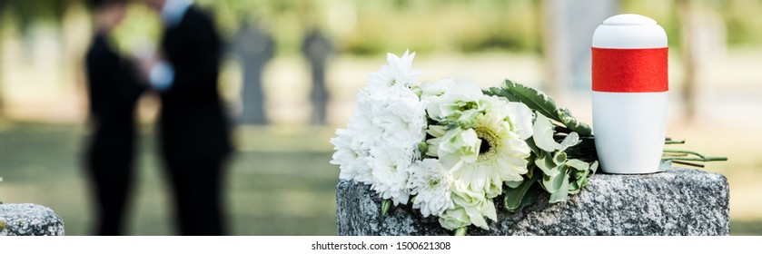 Panoramic Shot Of White Flowers And Cemetery Urn On Tombstone
