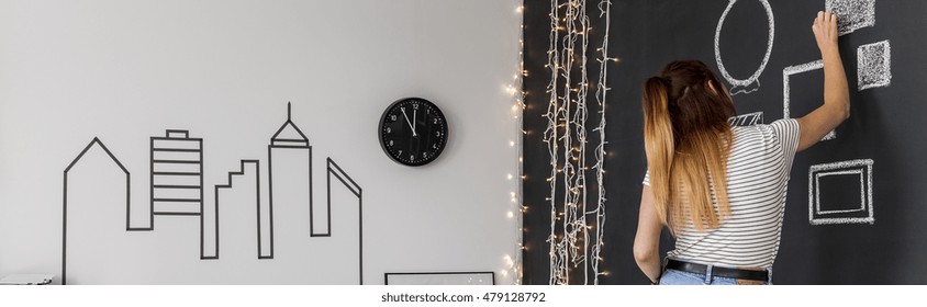 Panoramic Shot Of A Woman Drawing On A Black Chalkboard Wall In Her Bedroom