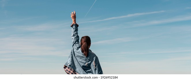 Panoramic shot of a woman rising hand in the sky