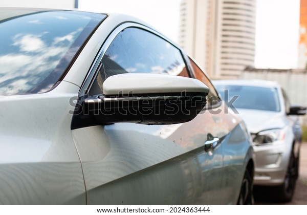 Panoramic side mirror of the car. The car is parked in a\
big city 