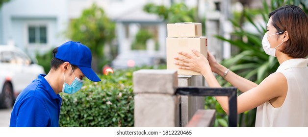 Panoramic Side View Asian Woman With Face Mask Customer Take Shopping Packages From Fence Post That Delivery Man Put Them On For Contactless Delivery. This Can Reduce Coronavirus COVID-19 Spreading.