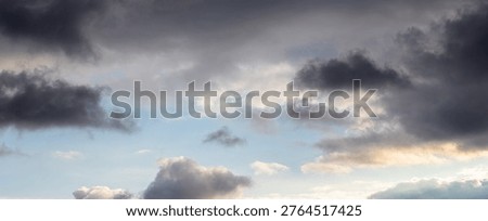 Panoramic sky with dark dramatic clouds on blue background and soft diffused light, variable cloudy weather