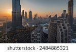 Panoramic skyline view of Dubai downtown during sunrise with mall, fountains and Burj Khalifa aerial morning timelapse. Modern skyscrapers and cloudy sky with sun rays