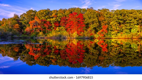 Panoramic stunning photo of fall foliage reflected on a lake with a glass-like mirror water surface