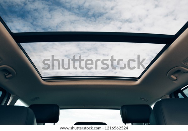 Panoramic sun roof at the\
car and blue sky. Clean sunroof and view at the sky from the inside\
or car interior