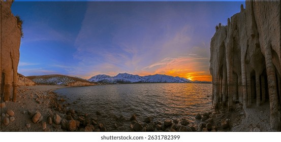 Panoramic sunset at Crowley Lake, California. Unique Stone Columns frame the view of the lake and distant mountains. Golden light reflects on water. Serene and majestic.