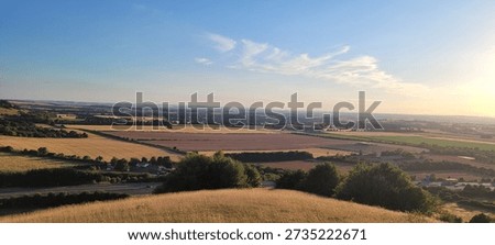Panoramic sunset view from Aston Rowant escarpment over Vale of Oxford, rolling fields and countryside patchwork under golden hour sky in Chilterns AONB