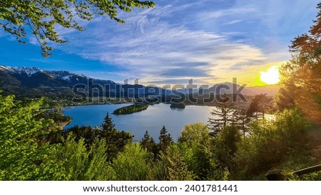 Panoramic sunset view on Lake Faak from Taborhoehe in Carinthia, Austria, Europe. Surrounded by high Austrian Alps mountains. Water surface reflecting soft sunlight. Remote alpine landscape in summer