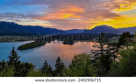 Panoramic sunset view on Lake Faak from Taborhoehe in Carinthia, Austria, Europe. Surrounded by high Austrian Alps mountains. Water surface reflecting soft sunlight. Remote alpine landscape in summer