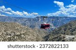 A panoramic sweep of Copper Canyon, featuring a cable car adorned with "Bienvenidos a Chihuahua" and "Barrancas del Cobre" welcoming tourists, as they revel in the spectacular landscape below.