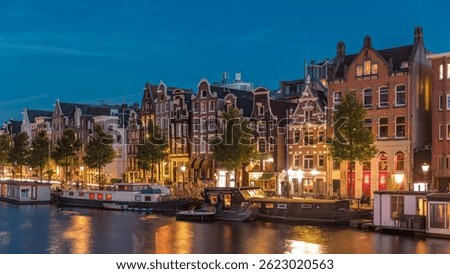 Panoramic timelapse hyperlapse of the illuminated famous Dancing Houses along the Amstel River day to night transition. Water channels with houseboats. Iconic landmark in Amsterdam, Netherlands